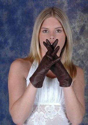 Blonde female pulls on brown leather gloves while wearing a white dress on chickinfo.com