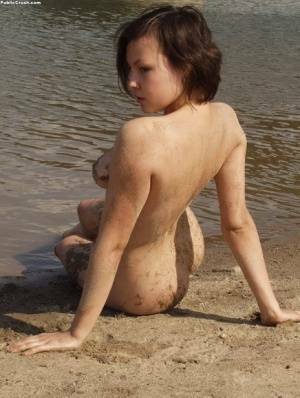 Amateur girl covers her naked body in sand while at a nude beach on chickinfo.com