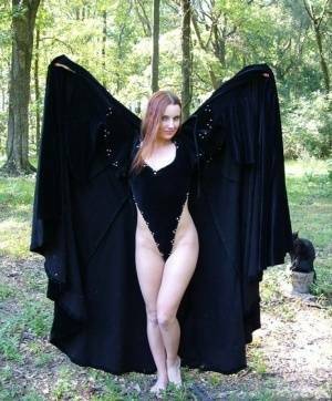 Redhead amateur Amber Lily models nude in a forest draped in a black cape on chickinfo.com