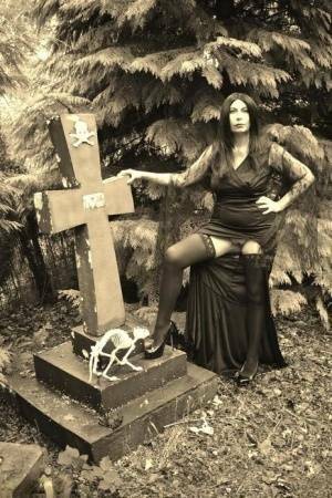 Goth girl Barby Slut bares her big tits and twat atop a casket in the woods on chickinfo.com