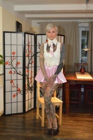 Tattooed platinum blonde Miss Francine models a raincoat over a latex dress on chickinfo.com