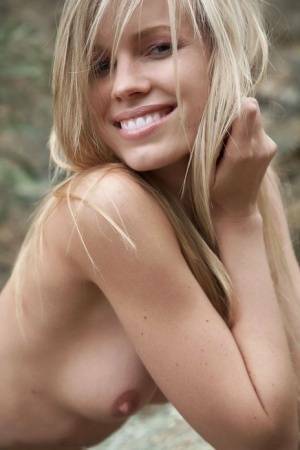Smiling MILF Marketa shows off her nude body atop a rock outdoors on chickinfo.com