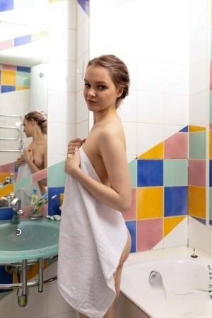 Petite teen Nicolle displays her phat ass while getting naked for a shower on chickinfo.com